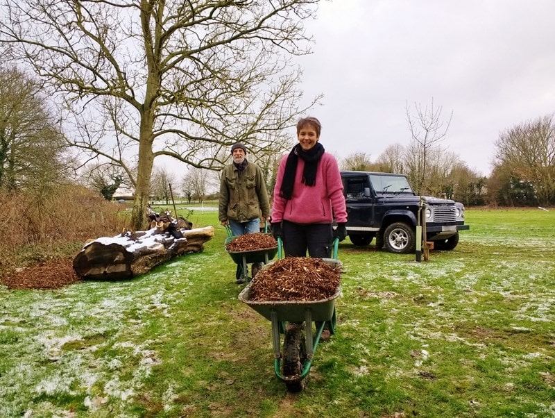 Councillor Buttle with a wheelbarrow of woodchip showing how its done