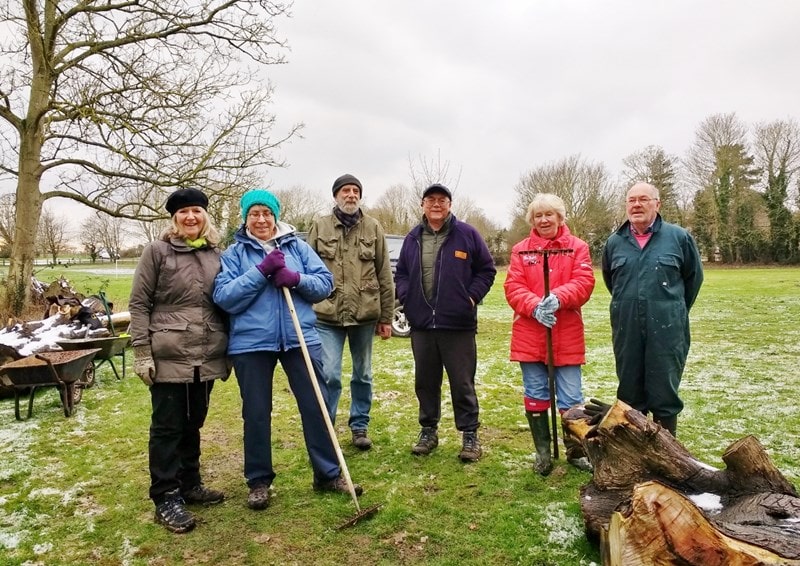 6 people working in the recreation ground renewing the woodland woodchip path